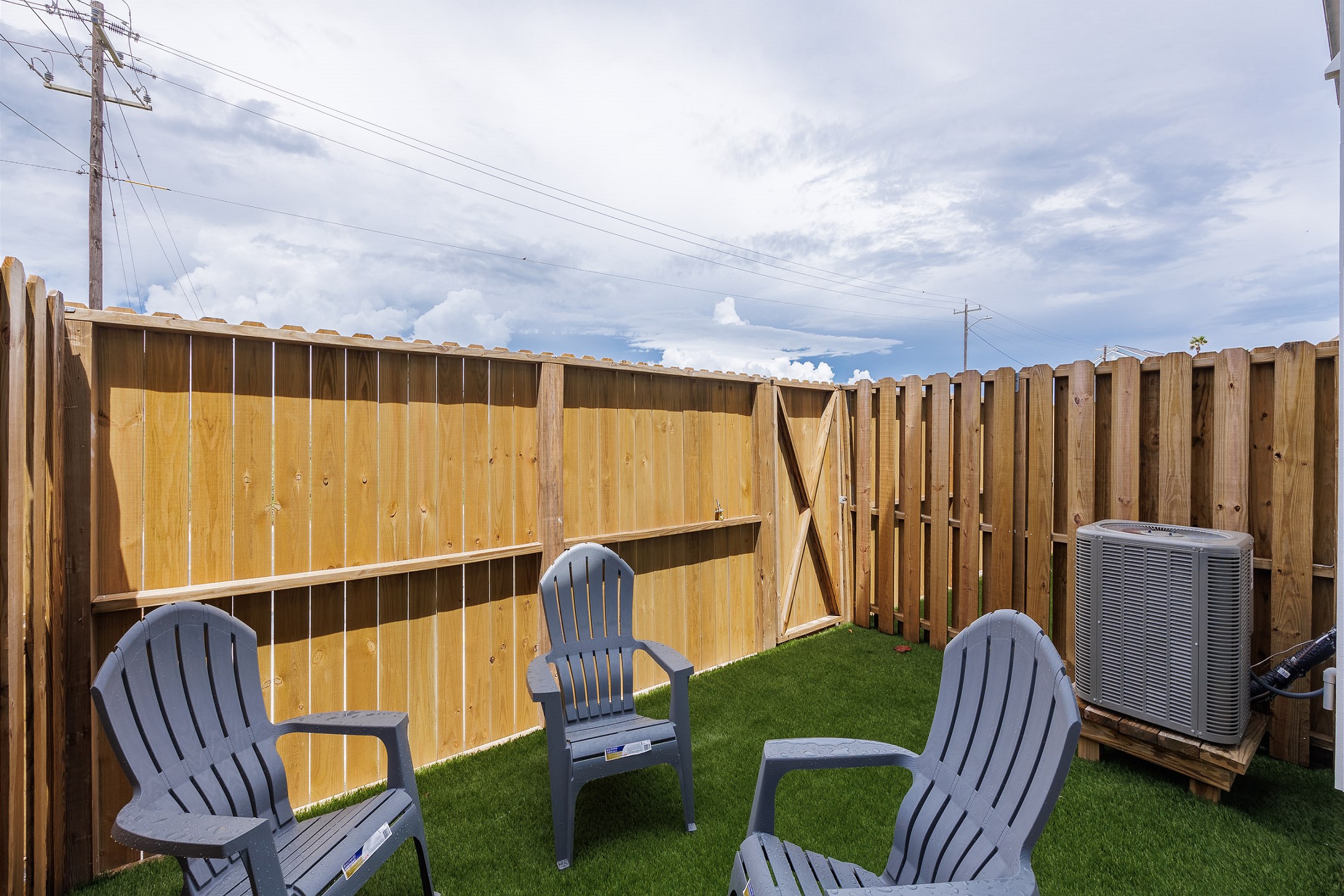 Private, fenced in patio off the master bedroom with chairs, turf grass, and access out the back gate 