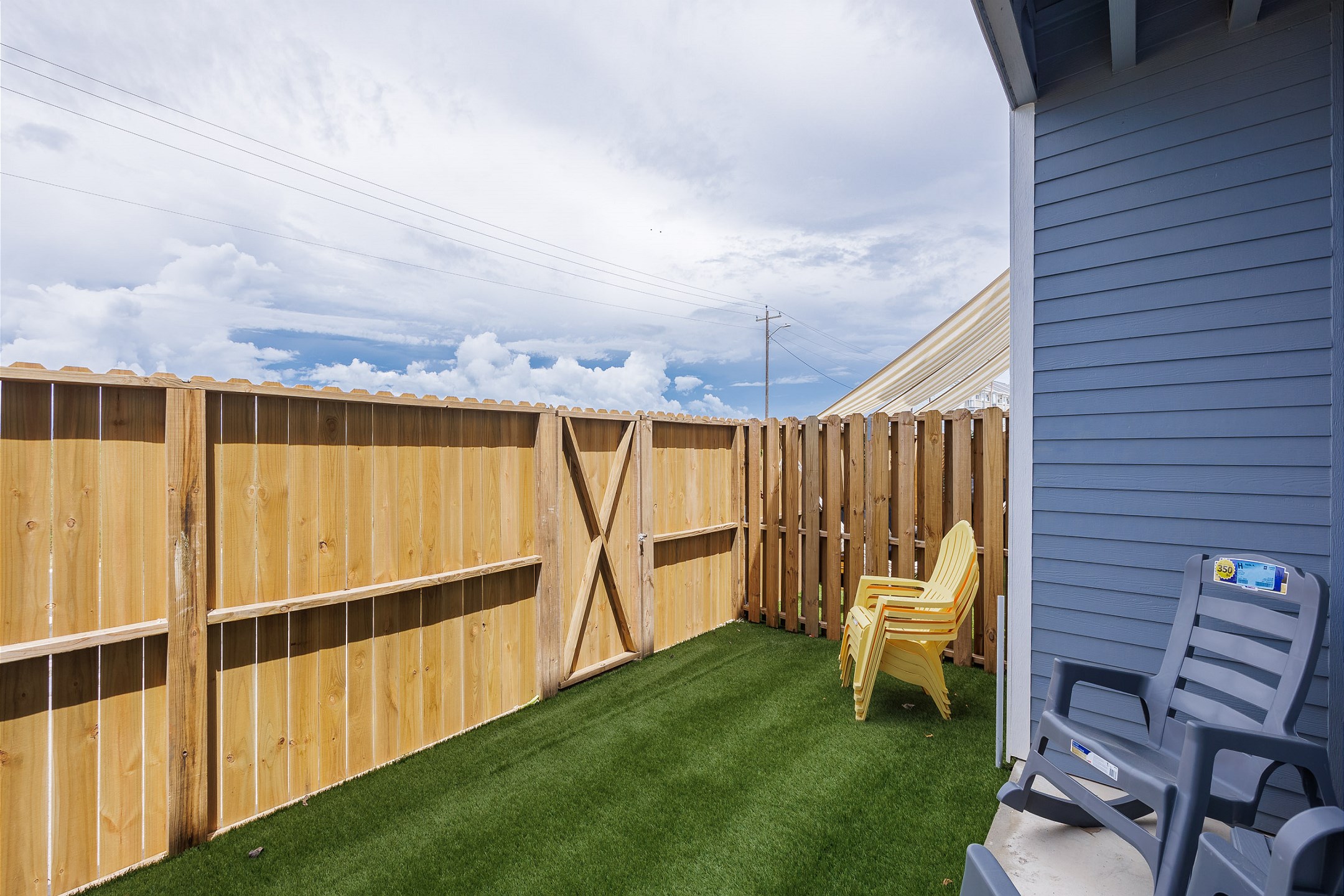 Private, fenced in patio off the master bedroom with chairs, turf grass, and access through the back gate 