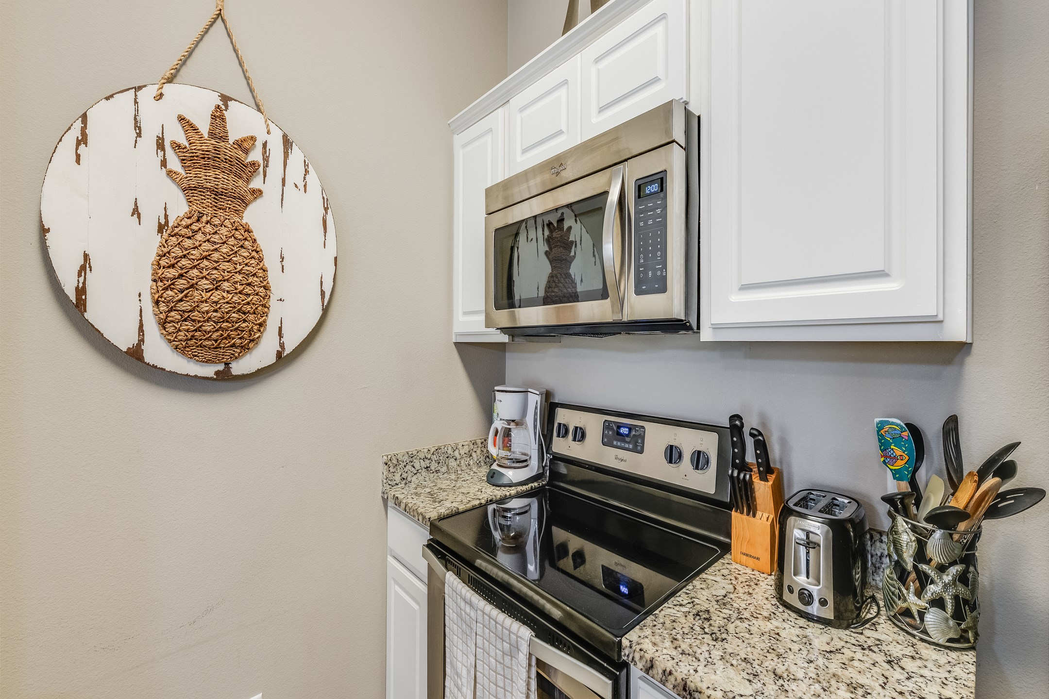 Fully equipped kitchen area with coffee maker, toaster, cookware, dinnerware, and other kitchen essentials provided