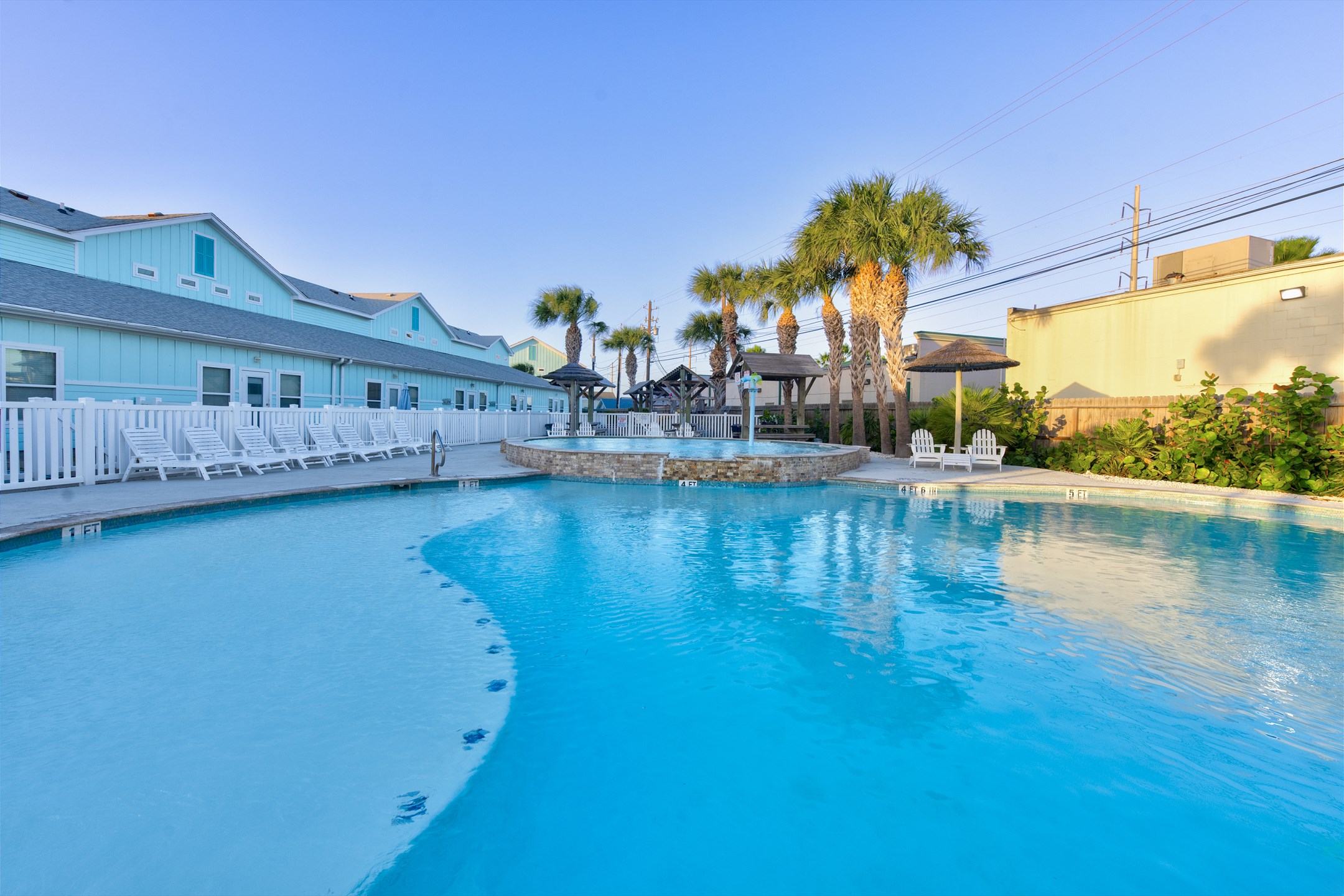 Dive into island vibes at this stunning pool, complete with water features, picnic tables and lounge chairs under Tiki huts