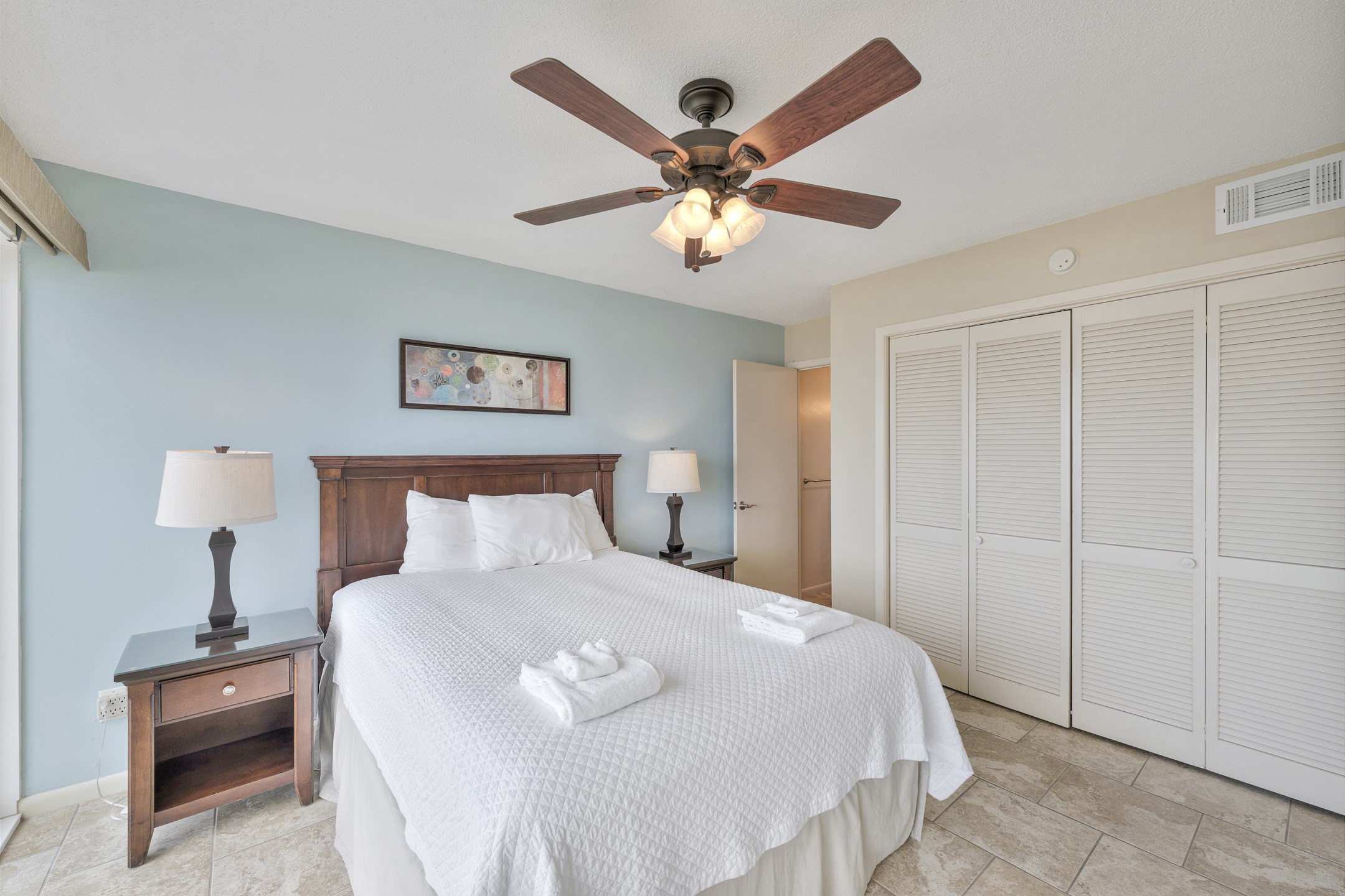 Primary bedroom with queen size bed, private bathroom and floor to ceiling windows offering a view of the beach - shutters that open up into the living area