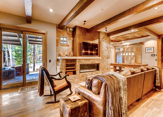 with large couch, fireplace and patio access with hot tub