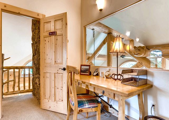 Study which overlooks the massive living room fireplace and hand carved decorative beams