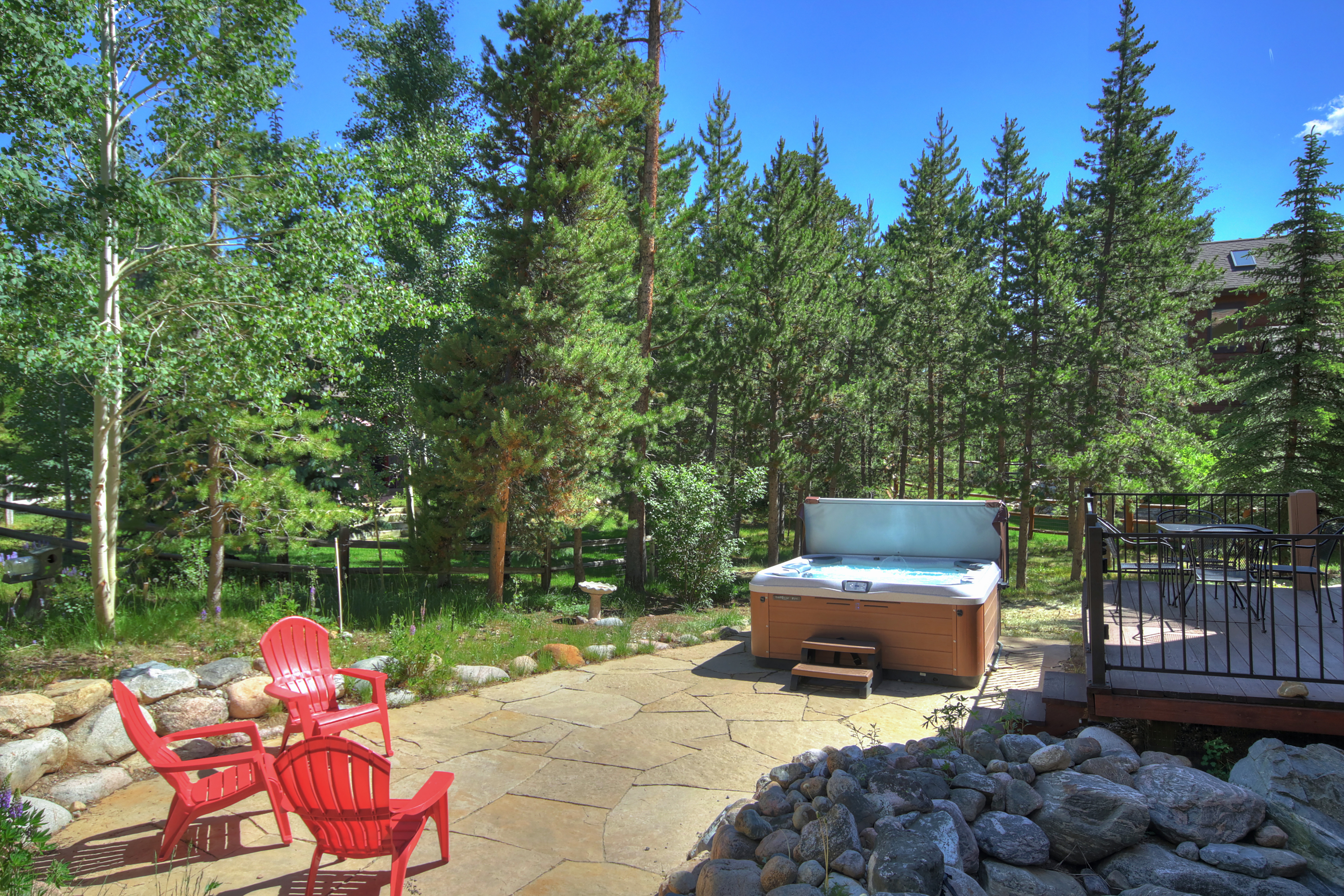 Outdoor stone patio with hot tub and seating - Buffalo Mountain Vista Frisco Vacation Rental