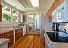 Koa wood, granite counters and white appliances in Koa Cottage kitchen with ocean views.