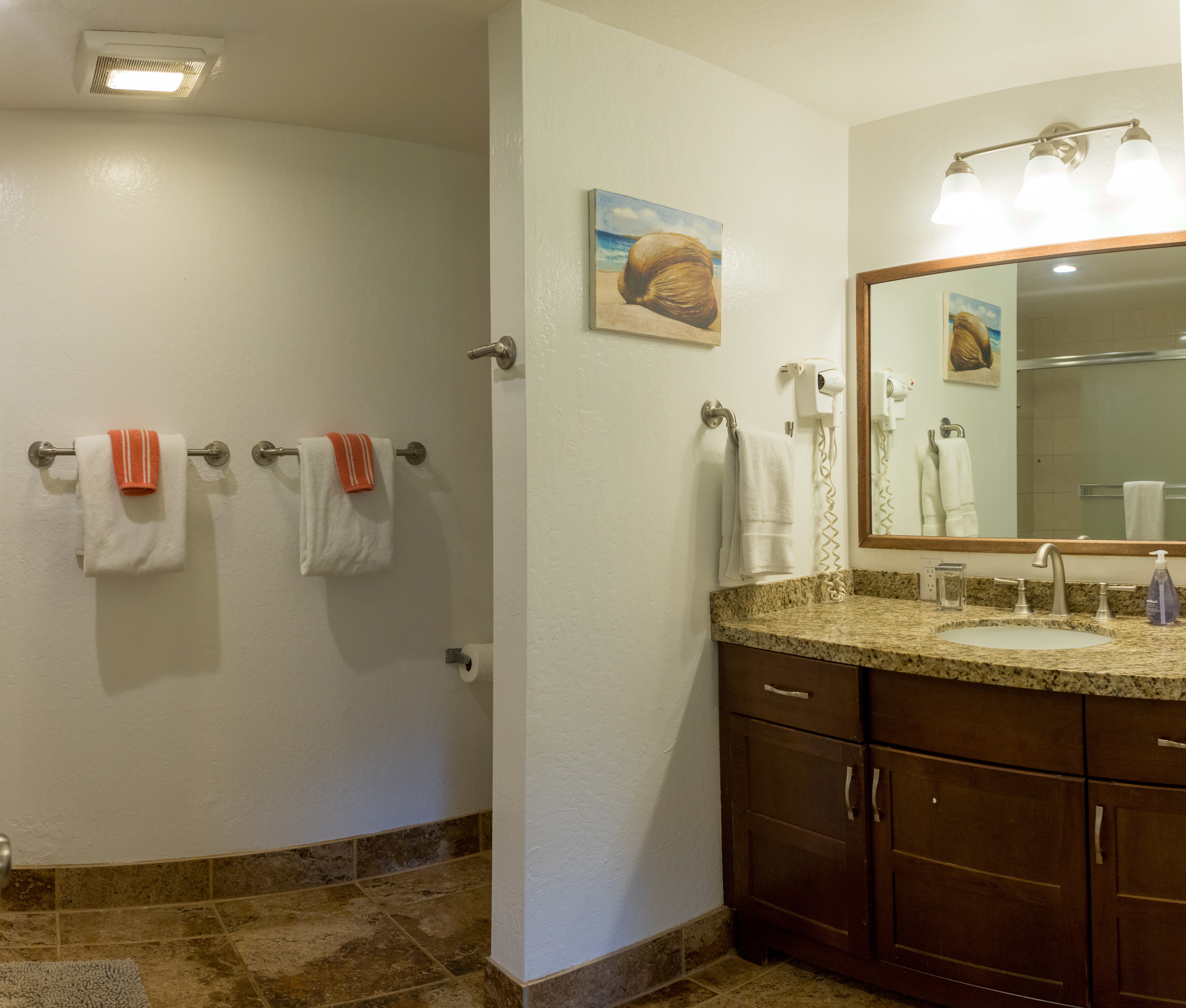 Kahala's master bathroom features a tub with shower, hairdryer and seaside accents.