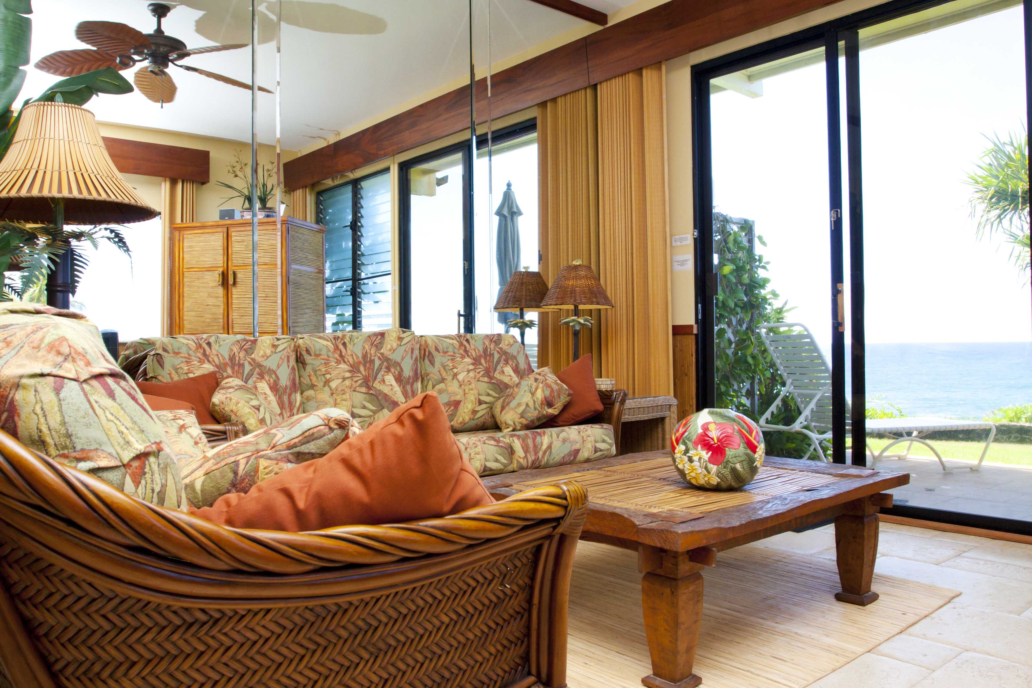 Beautifully furnished and appointed oceanfront living room that opens onto the grassy lawn.  Enjoy the birds playing and singing in the beautiful LauHala tree just outside the patio.