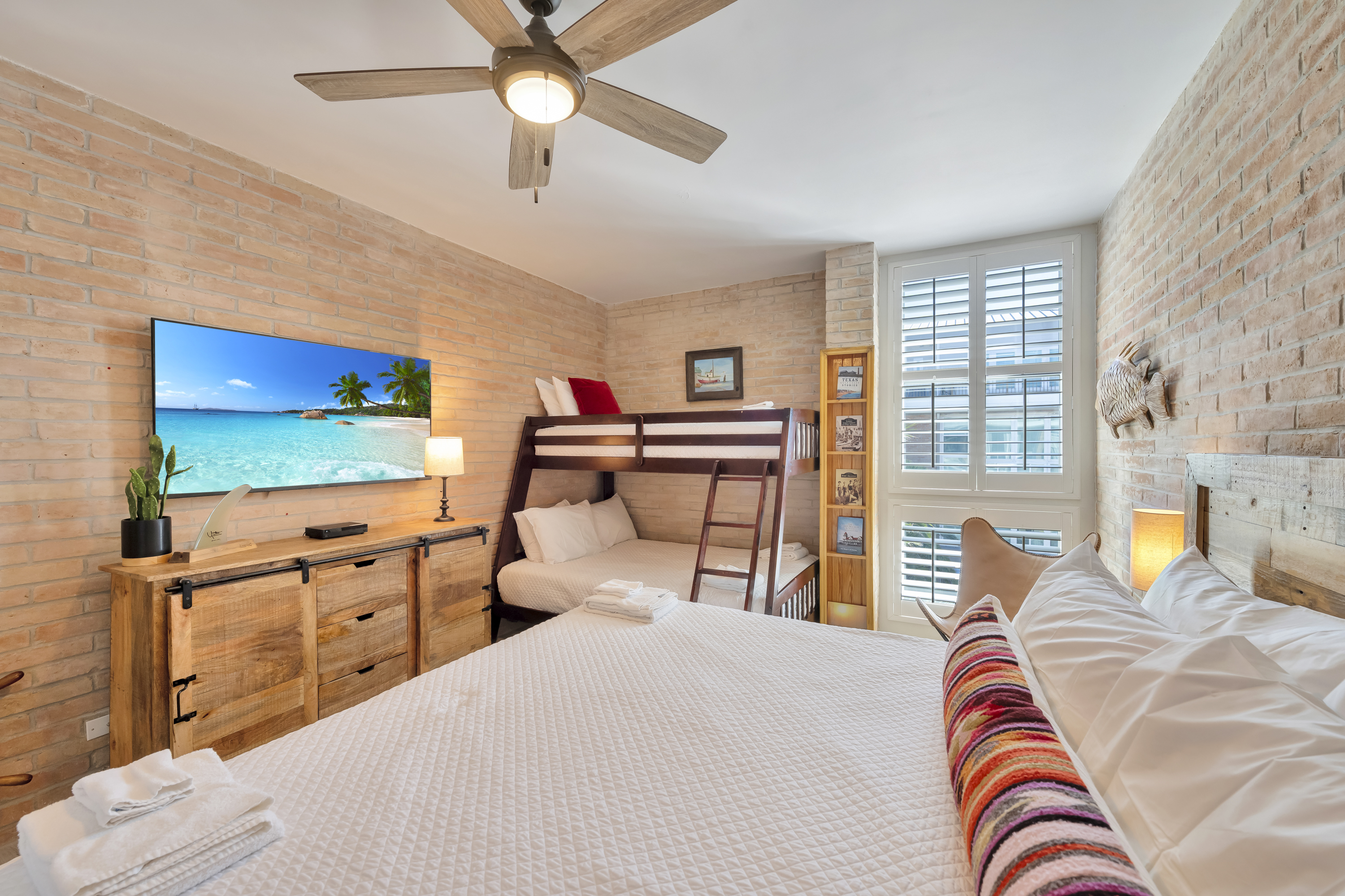 Relax in the main bedroom featuring a king-size bed, twin-over-full bunks, and a large TV—ideal for unwinding after a day of fun.