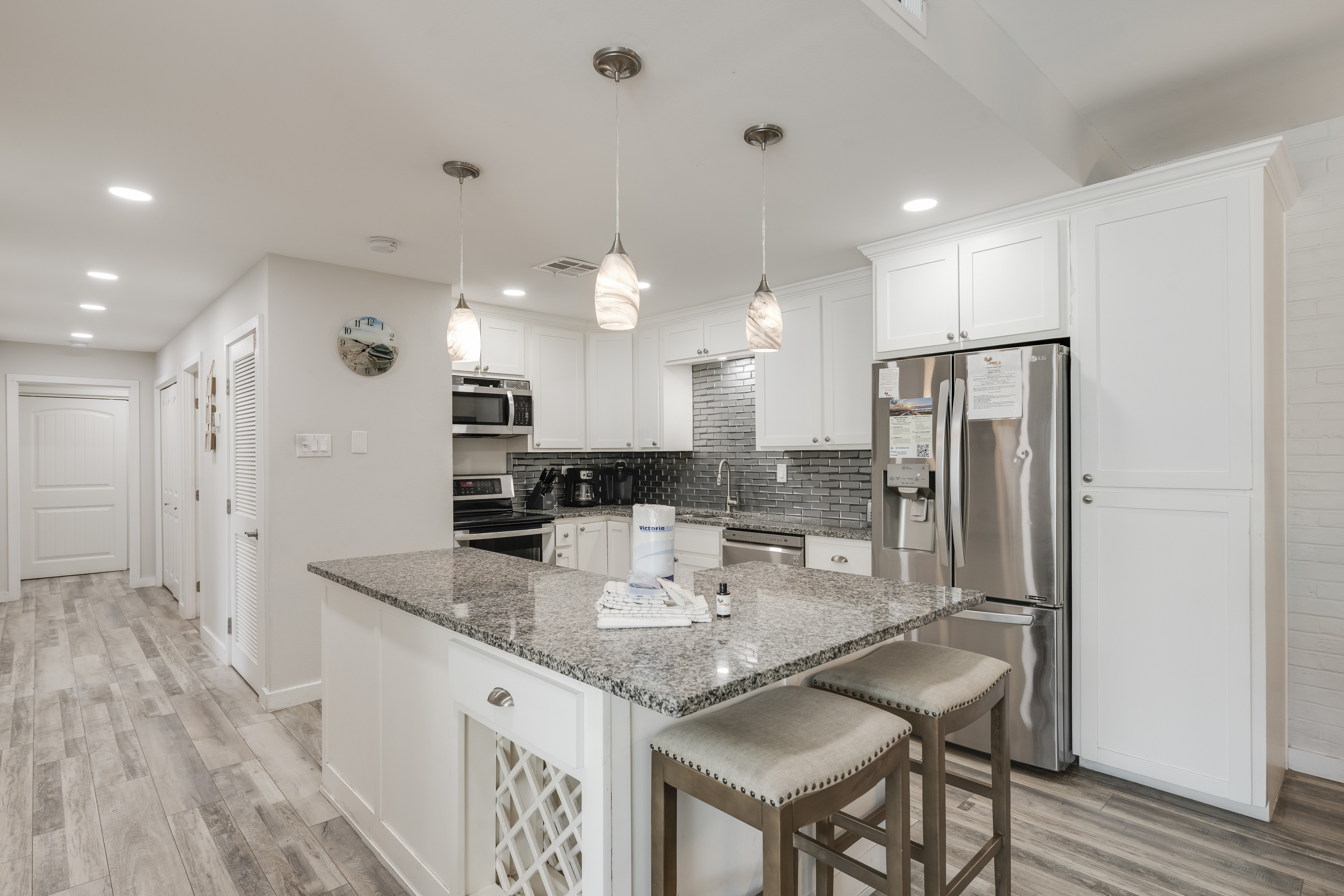 Bright, modern kitchen featuring a granite-topped island with seating for two
