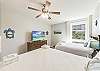 Coastal-themed bedroom featuring two full-sized beds, flat screen Tv and wooden dresser for extra storage