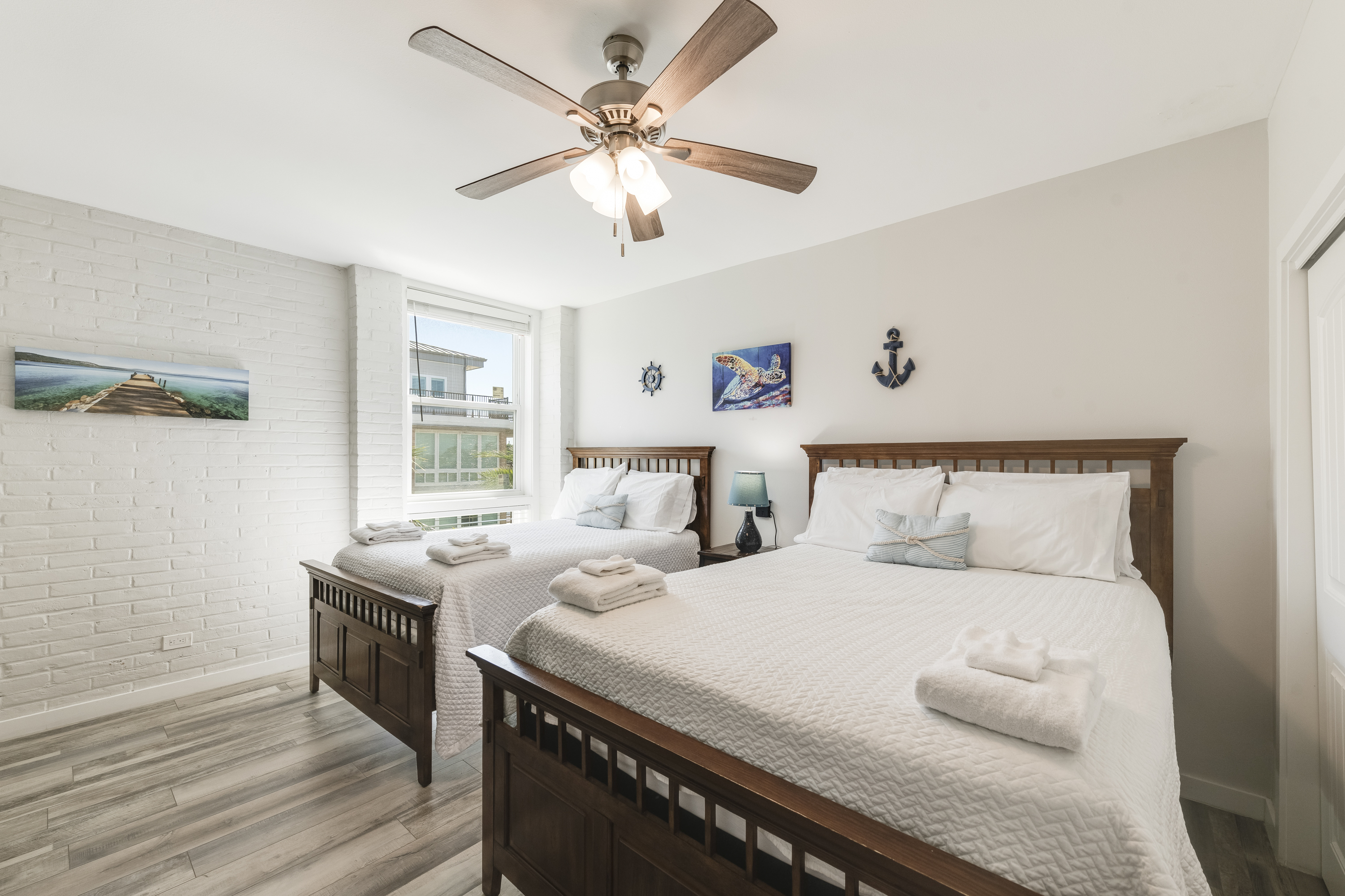 bright, coastal-themed bedroom featuring two full beds