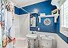 Bathroom with shower, pedestal sink, and toilet.