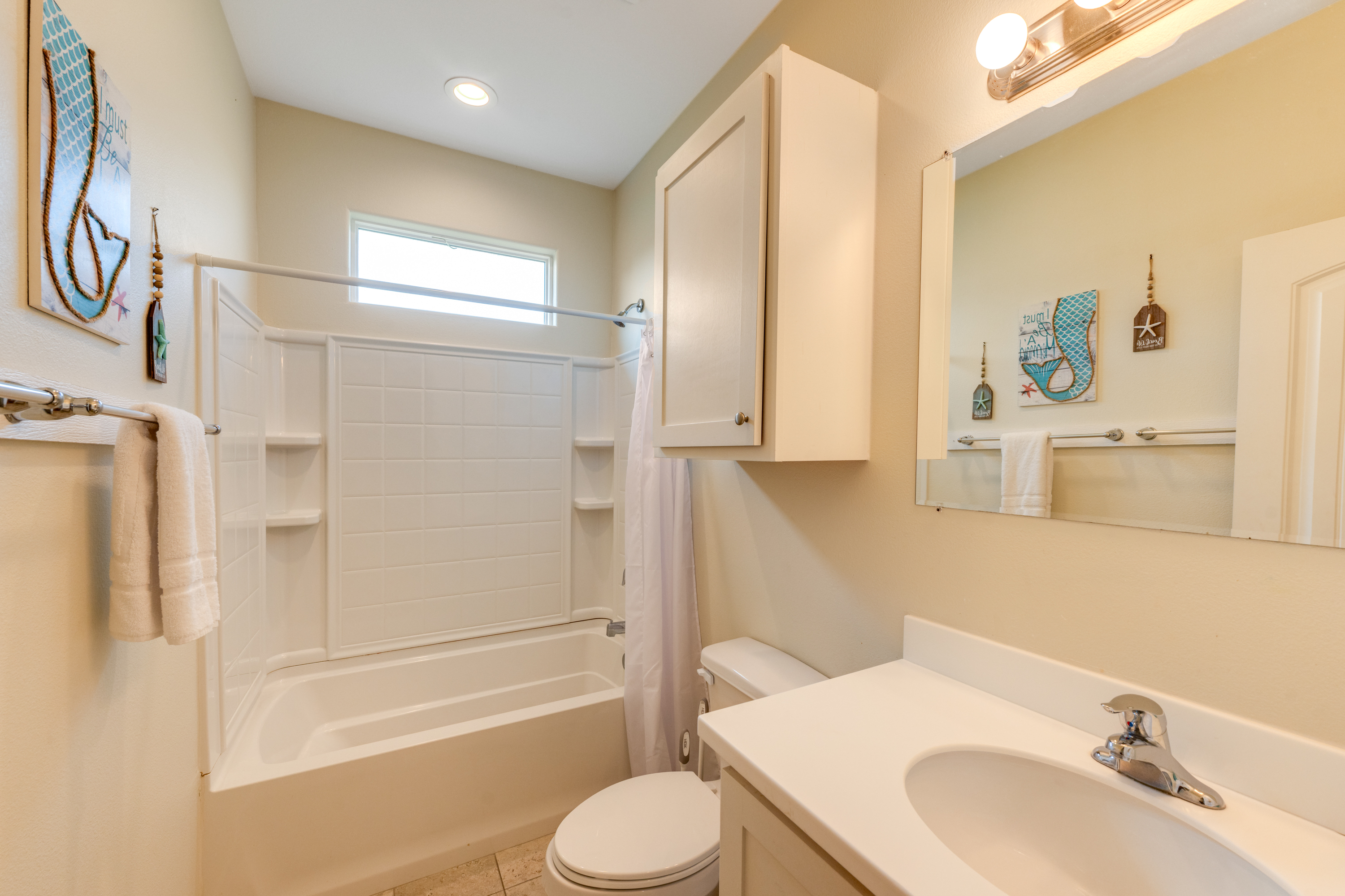Sparkling full bathroom features a tub/shower combo and cheerful coastal décor