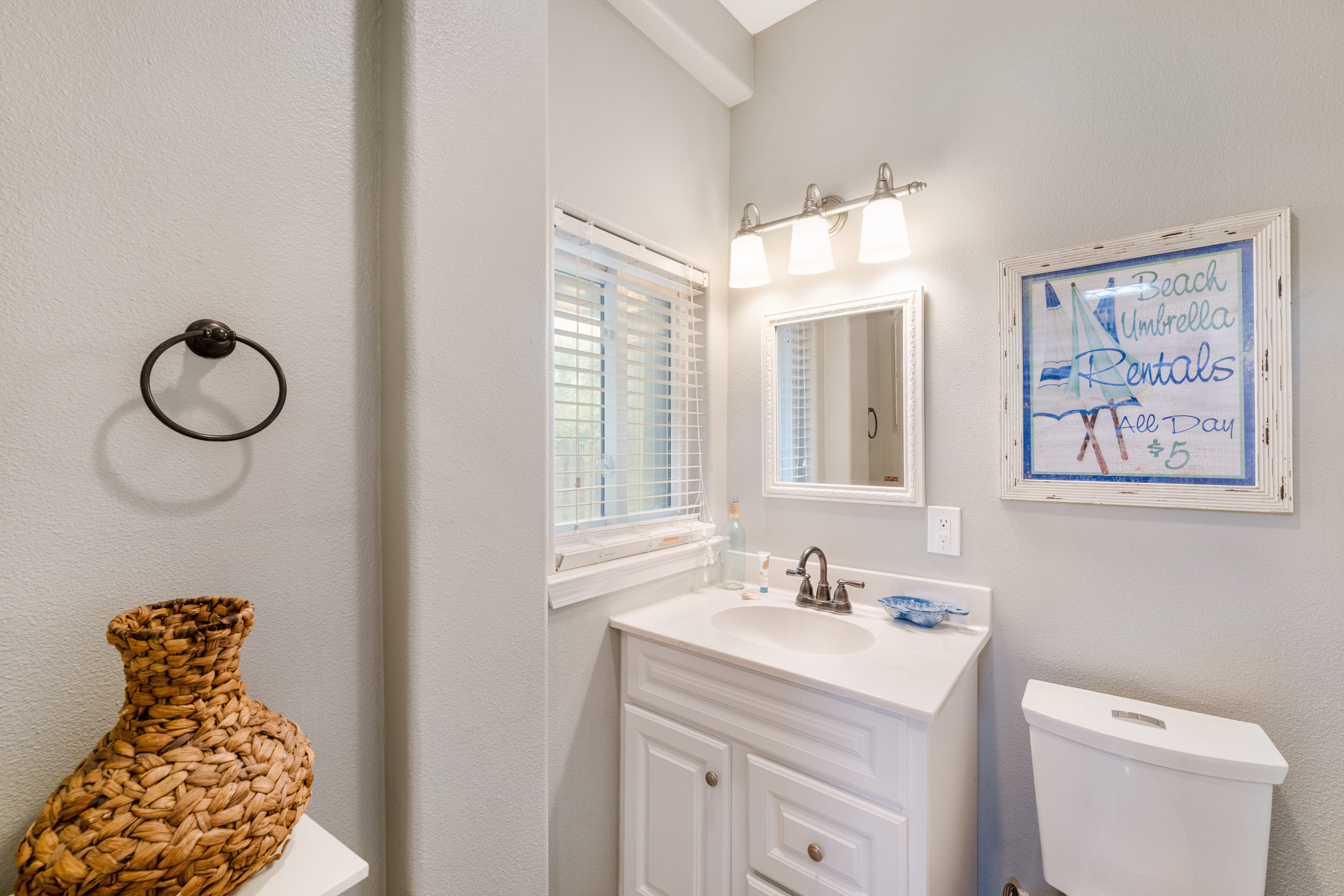 Bright, beachy half bathroom featuring crisp white finishes and coastal touches 