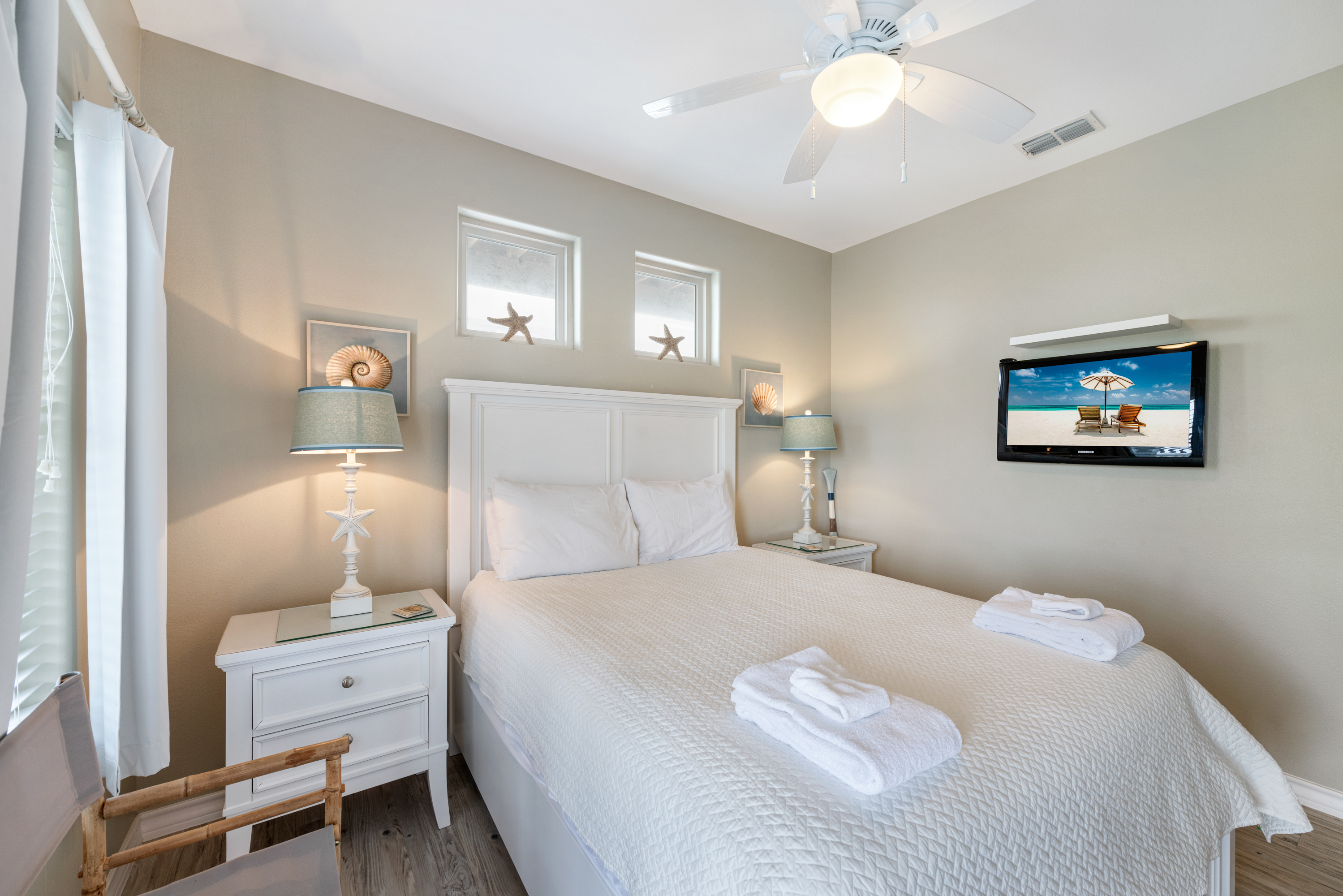Unwind in style in this bright, coastal-inspired Queen bedroom with TV.