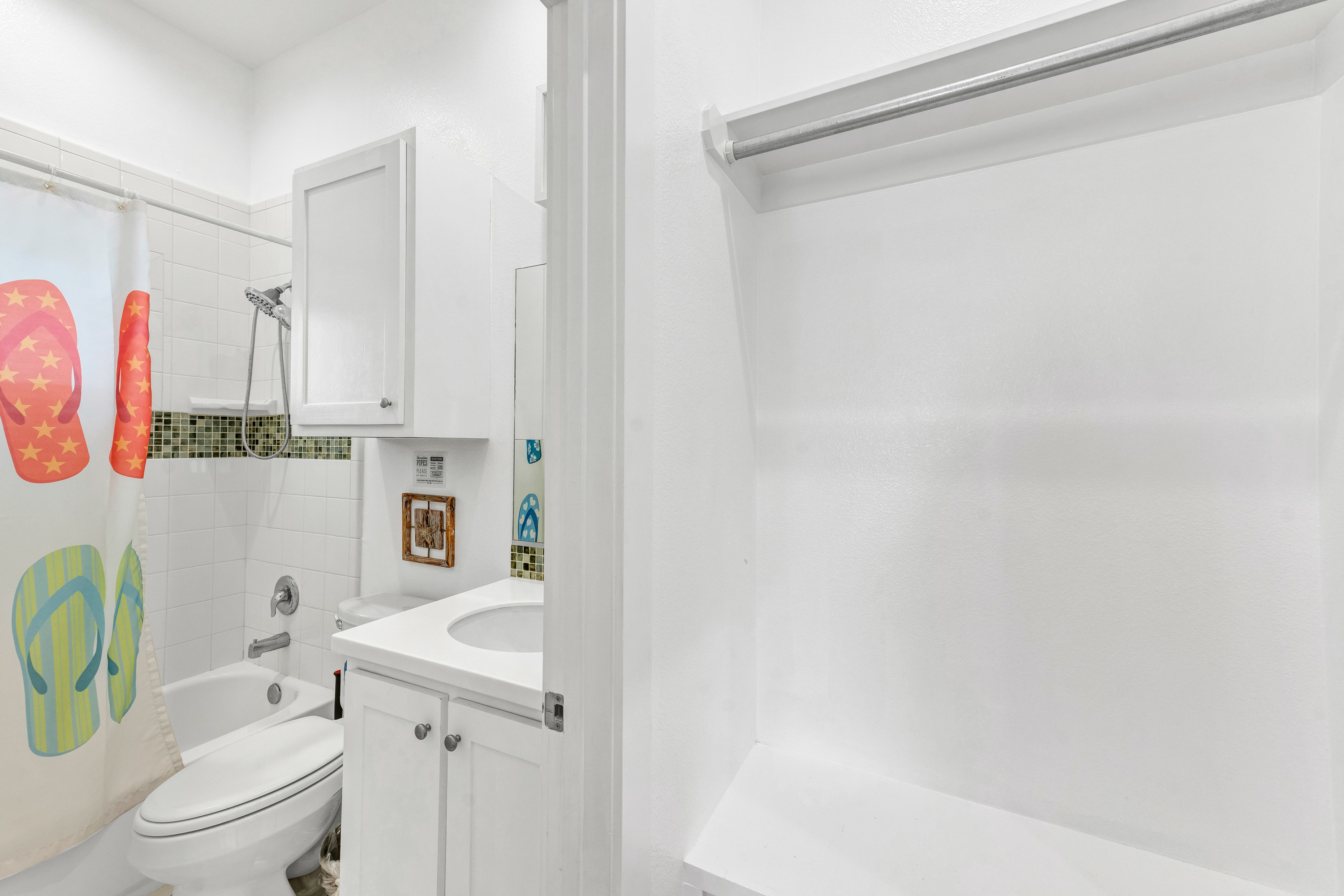 Bright, beachy full bathroom featuring crisp white finishes and coastal touches — the perfect spot to rinse off after a day in the sand.
