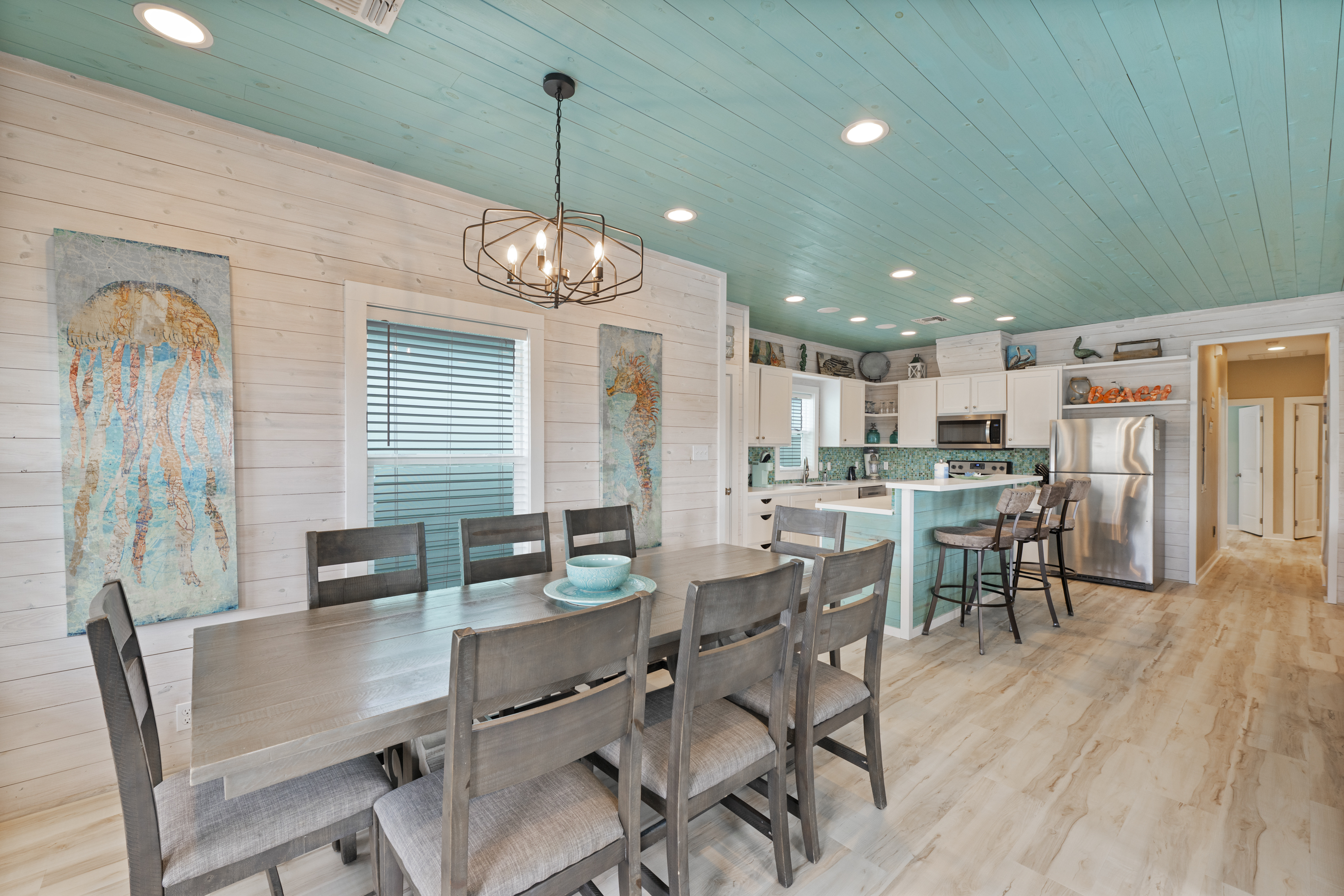 The open-concept living and dining area provides a comfortable space for everyone to gather. The living room offers cozy seating and a TV for relaxing after a day of exploring, while the nearby dining table is perfect for enjoying meals, playing games, or