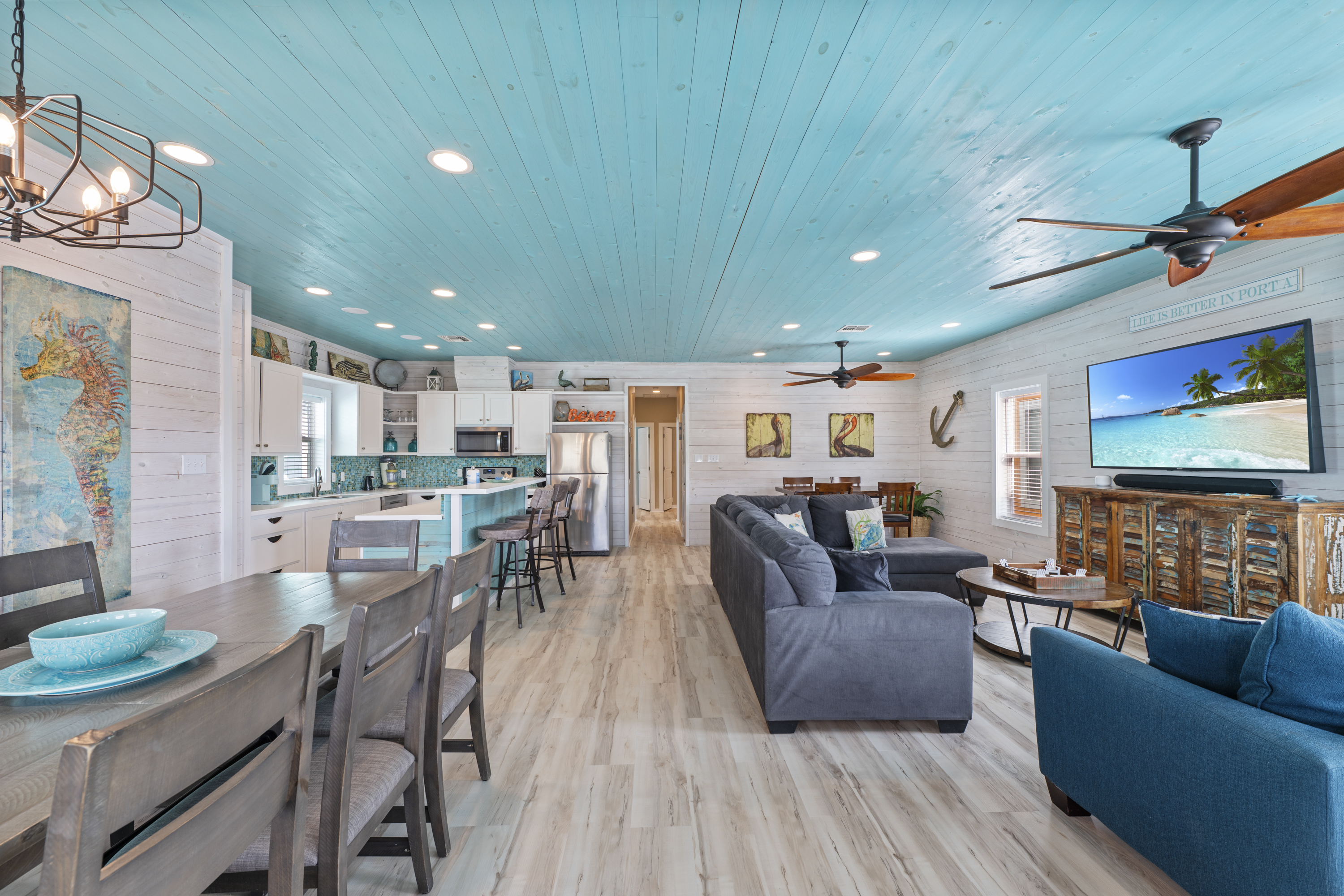 The open-concept living and dining area provides a comfortable space for everyone to gather. The living room offers cozy seating and a TV for relaxing after a day of exploring, while the nearby dining table is perfect for enjoying meals, playing games, or