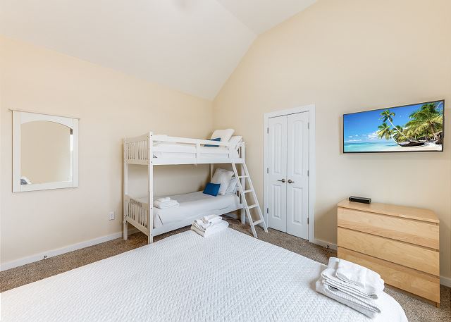 Spacious second-floor bedroom with plush queen bed and twin-over-twin bunk beds for versatile sleeping.