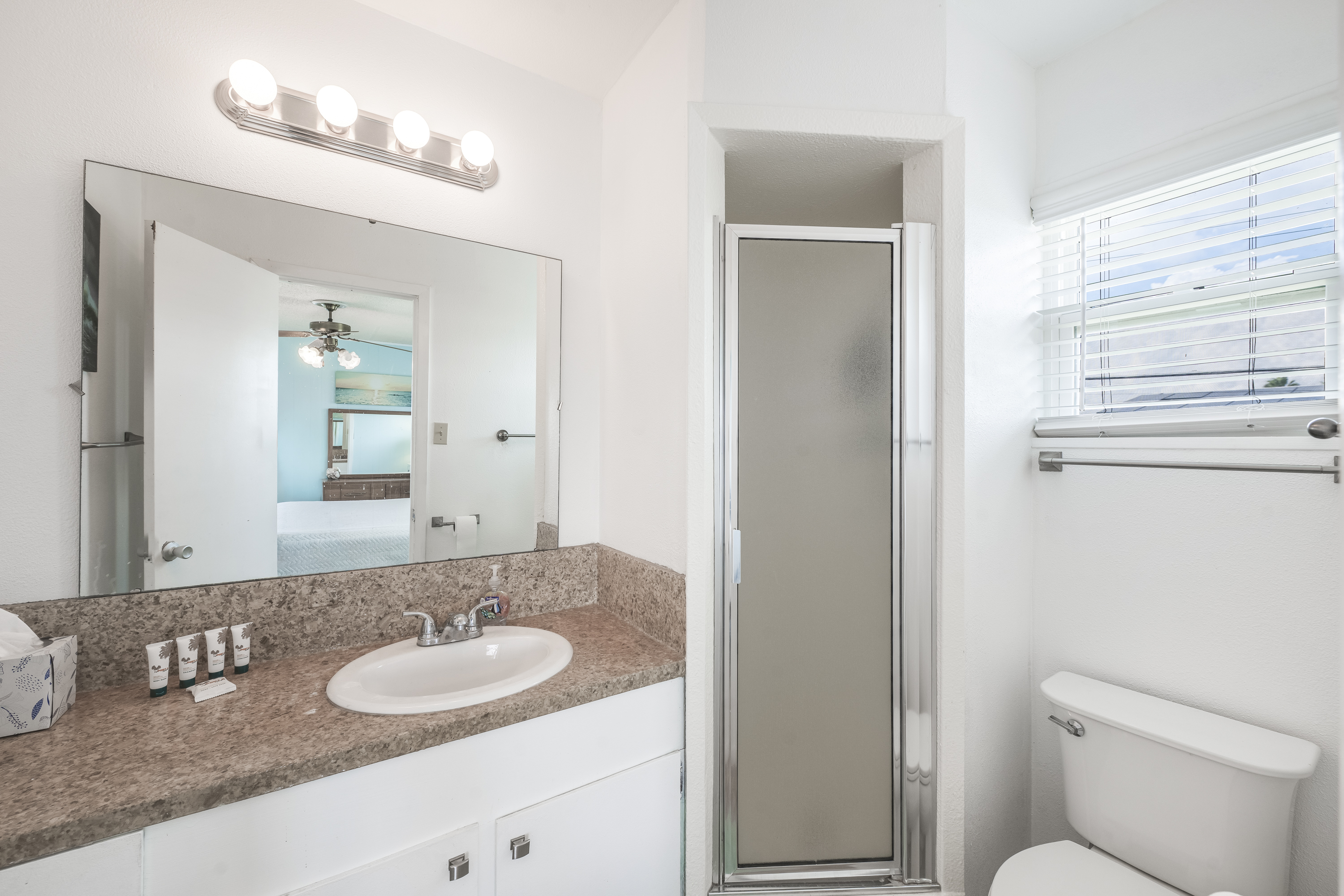 This clean and bright ensuite bathroom offers a walk-in shower for easy convenience, while the spacious countertop and large mirror make getting ready effortless