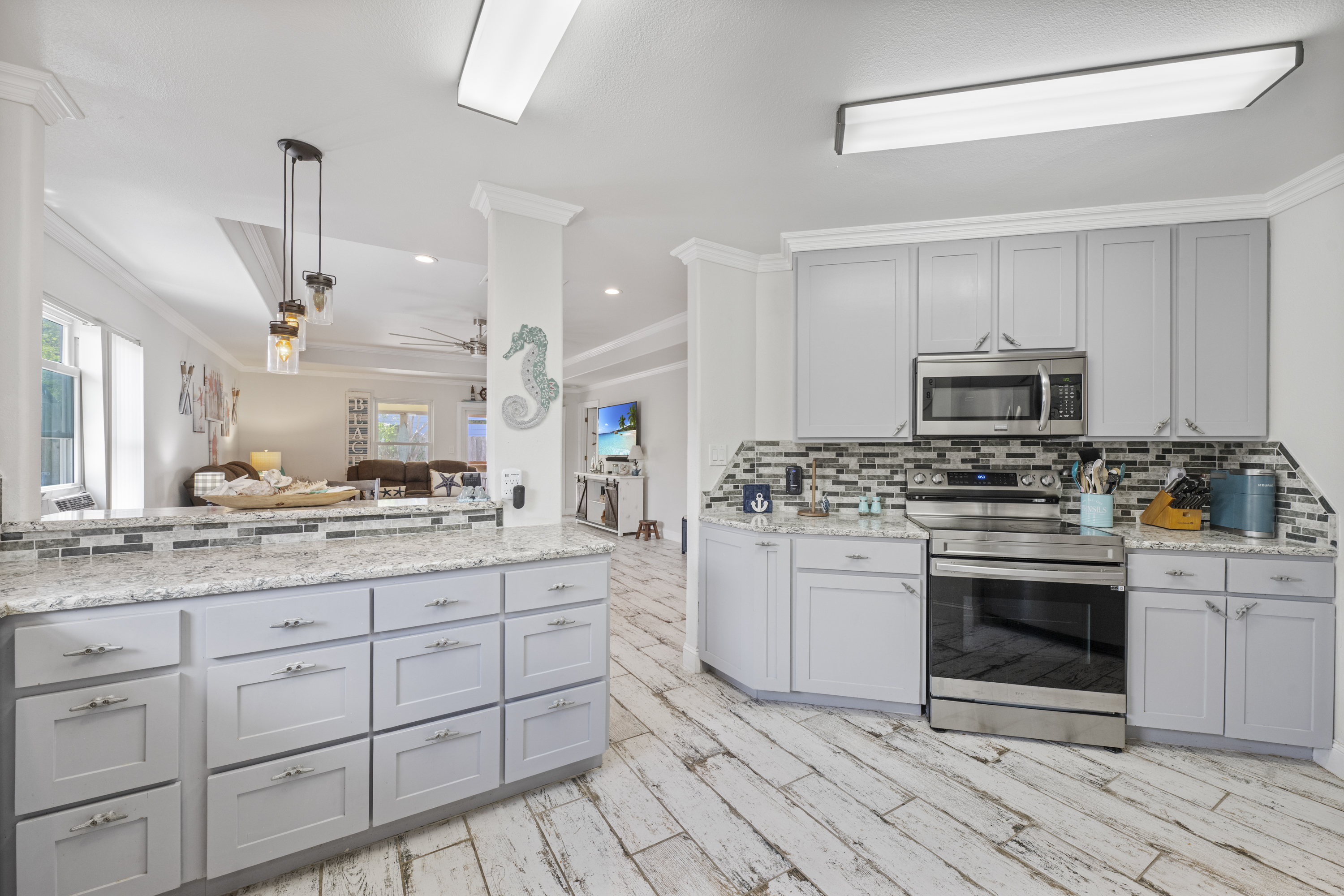 Inviting Coastal Kitchen Overlooking Bright, Social Living and Dining Spaces
