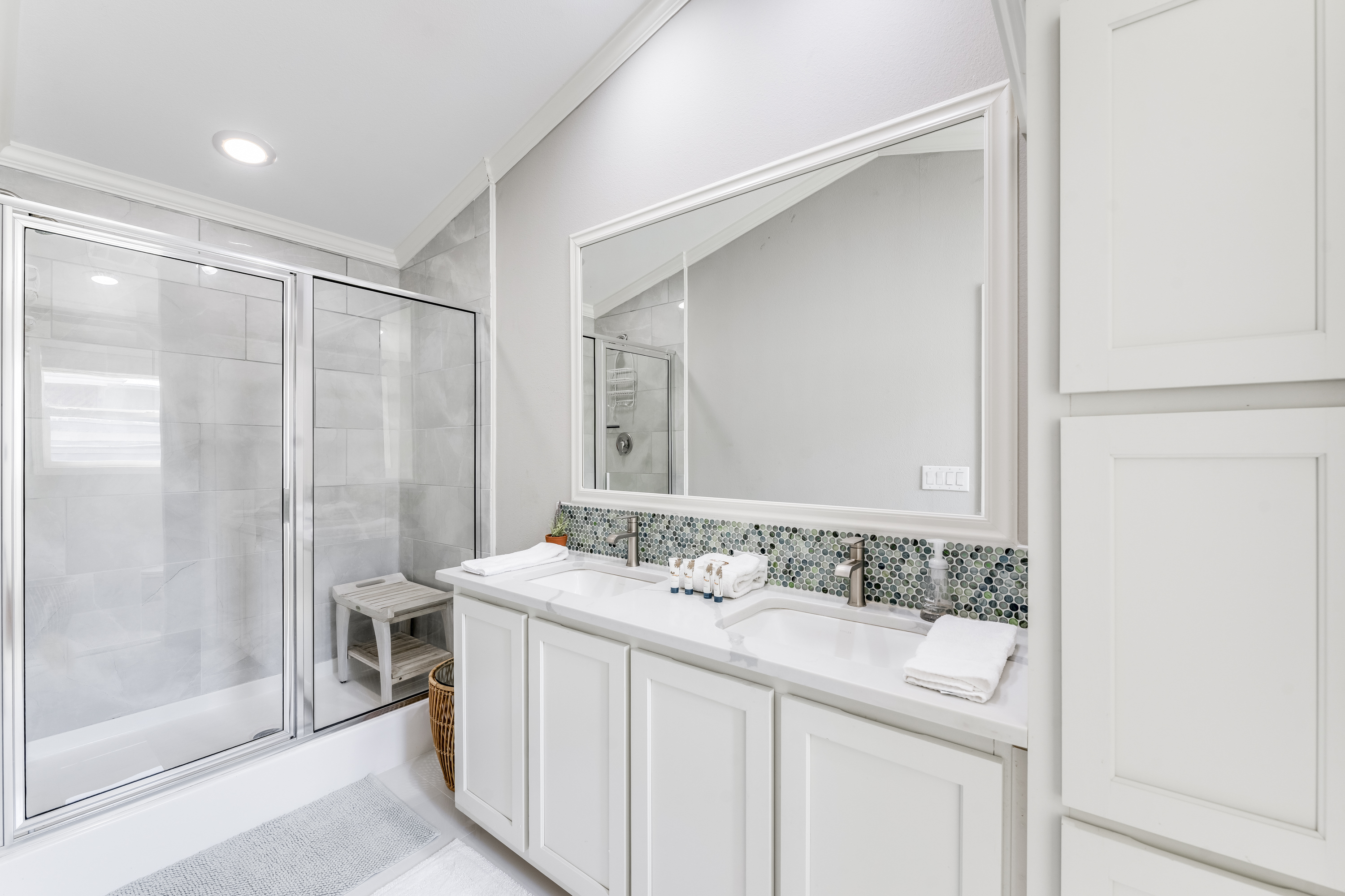 The full bathroom blends modern design with coastal charm, featuring glass shower doors, soft lighting, and elegant finishes that create a relaxing, spa-like feel