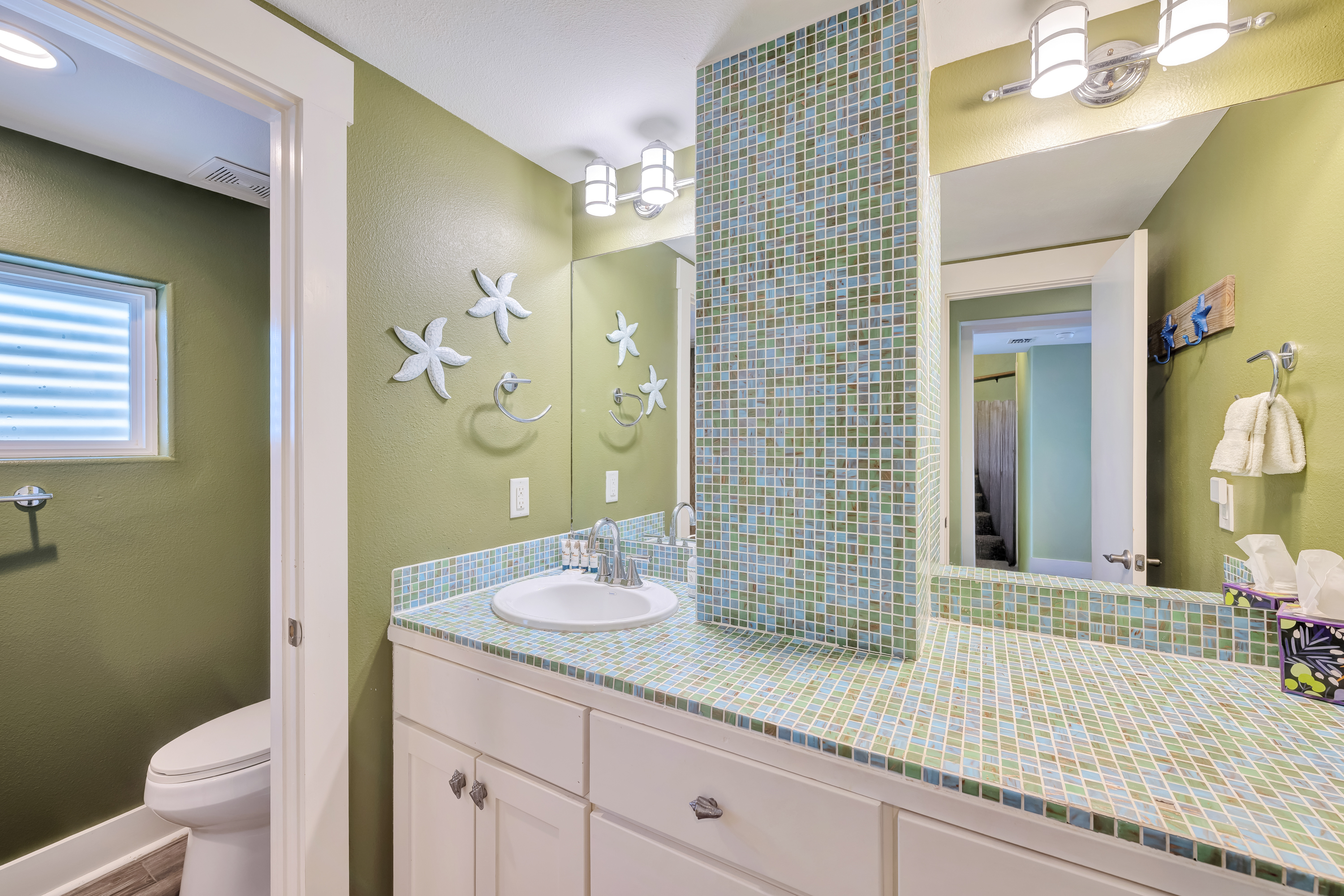 This stylish shared 1st Floor bath features a tiled walk-in shower, spacious vanity, and a calm, coastal color palette for a relaxing refresh