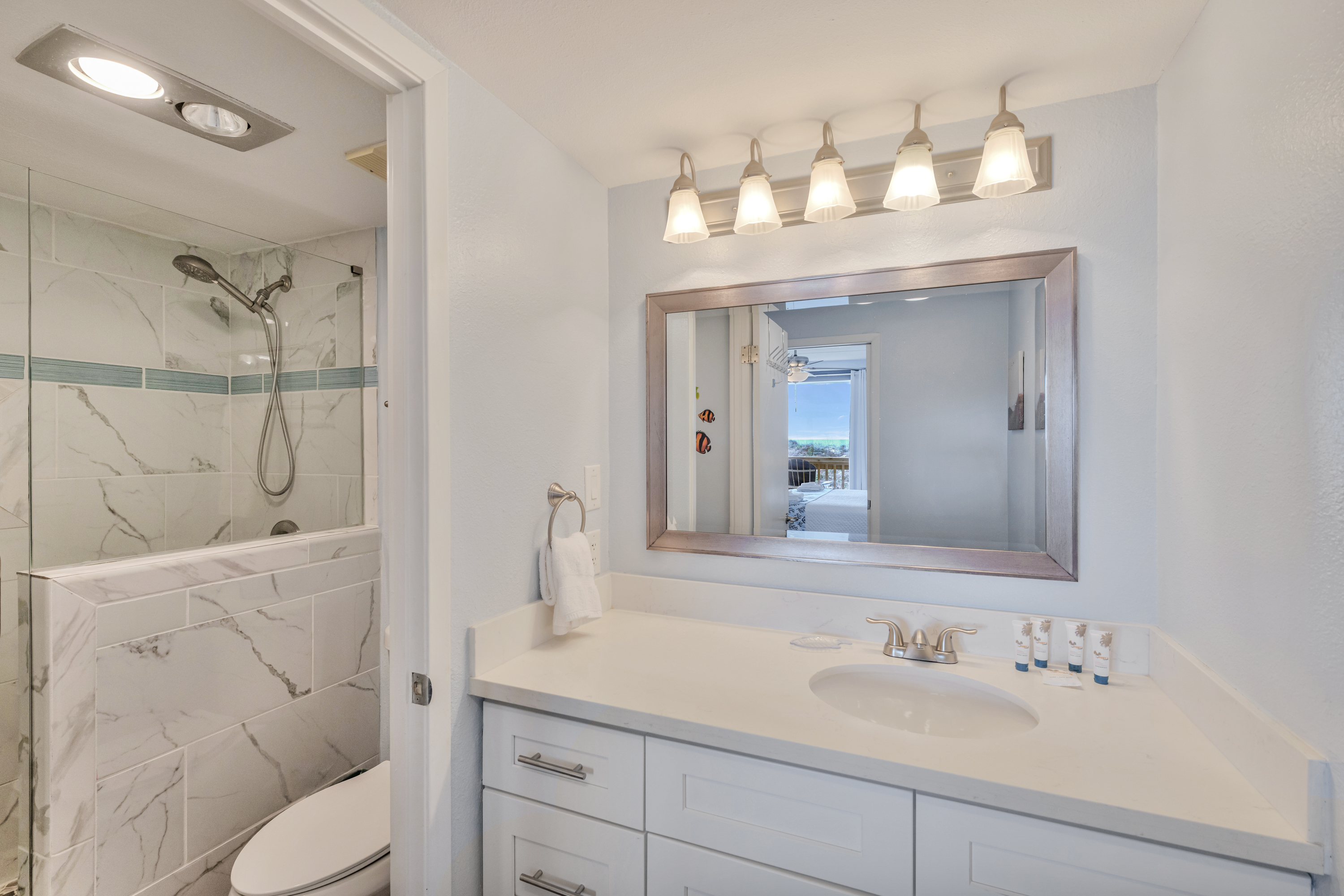 Elegant white bathroom with plenty of counter space and a beautifully lit mirror for the ultimate luxurious feel.