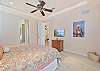 The primary bedroom features a king size bed and flat screen TV. The french doors open up to the pool area