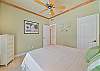 Beach style decorated guest bedroom with Queen size bed, and sliding doors to the screened in pool area.
