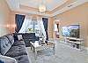 Living with large flat screen TV and sliding doors opening to the screened in balcony.