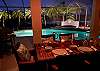 Outdoor dining overlooking the illuminated pool and palm trees