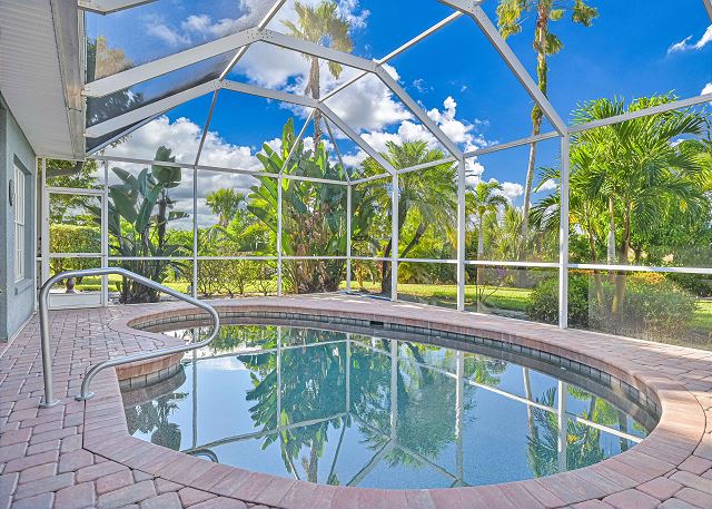 The private, heated pool is surrounded by lush landscaping