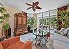 Living area with flat screen smart TV and sliding doors opening to the screened in lanai and terrace