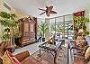 Living area with flat screen smart TV and sliding doors opening to the screened in lanai and terrace