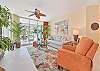 Living area with flat screen smart TV and sliding doors opening to the screened in lanai and terrace