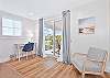 An office nook and seating area  in the upstairs primary bedroom. The sliding doors provide access to the balcony with view to the bayside canal 