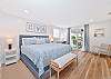 A king size bed, office nook and smart TV  in the upstairs primary bedroom. Sliding doors provide access to the balcony with view to the bayside canal