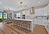 The chef’s kitchen features white shaker cabinetry, Quartz countertops, a large waterfall island with seating for four, double wall ovens, stainless appliances and a coffee bar. 