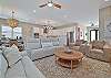 The bright open floor plan has wood-look flooring throughout and coastal décor. The living room offers two reclining sofas, extra seating and a large flat screen TV with cable. Sliding door open up to the pool area