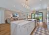 The chef’s kitchen features white shaker cabinetry, Quartz countertops, a large waterfall island with seating for four, double wall ovens, stainless appliances and a coffee bar. 