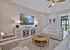 The bright open floor plan has wood-look flooring throughout and coastal décor. The living room offers two reclining sofas, extra seating and a large flat screen TV with cable. Sliding door open up to the pool area