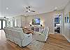 The bright open floor plan has wood-look flooring throughout and coastal décor. The living room offers two reclining sofas, extra seating and a large flat screen TV with cable. Sliding door open up to the pool area