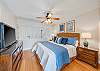 Comfortable king bedroom with ceiling fan, flat-screen TV, and charming island-style details