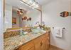 Bright bathroom with granite vanity, vessel sink, and tropical decor.