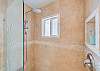 Spacious tiled shower with rainfall and handheld showerheads.