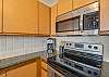 Kitchen corner with stainless microwave, stove, coffee maker, and cabinets.