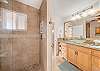 Elegant bathroom with walk-in tiled shower, sinks, and granite vanity.