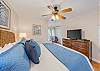 Spacious bedroom featuring modern amenities, flat-screen TV and ceiling fan