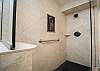 Walk-in shower with natural stone tile and custom mosaic accent.